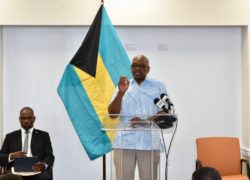 Prime Minister Minnis (at podium), and Mr. Lewis